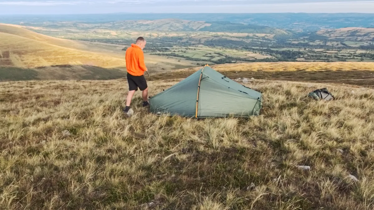 Pitching a tent on open moorland in low evening light